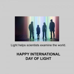 Silhouetted figures of scientists standing in front of a bright light spectrum with text celebrating International Day of Light.