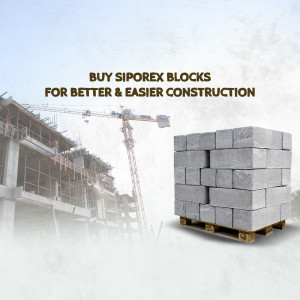 Siporex blocks stacked on a pallet with a construction site in the background