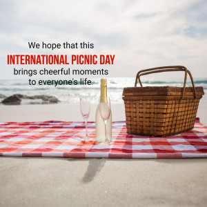 Picnic basket, wine glasses, and bottle on a beach blanket with ocean background