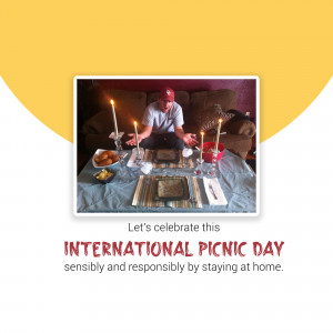 A man sitting at a picnic setup indoors with candles and food, celebrating International Picnic Day.