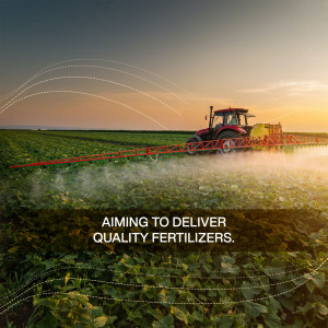 Tractor spraying fertilizer on a field at sunset