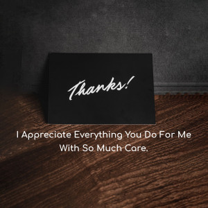 Black thank you card with white script on a wooden surface