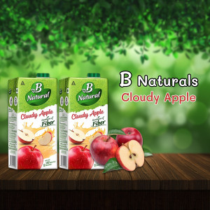 Two cartons of B Naturals Cloudy Apple juice with apples on a wooden surface.