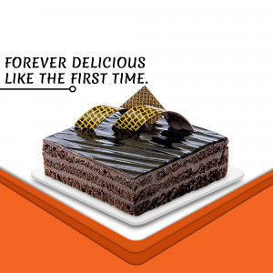 A square chocolate cake with a glossy dark chocolate glaze and golden lattice decorations, presented on a white plate.