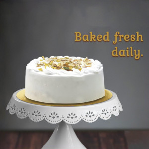 A white cake with almond flakes on top, displayed on a white cake stand.