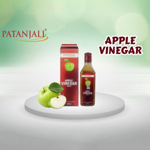 Patanjali Apple Vinegar bottle and apple fruit on a white surface