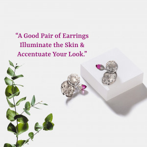 Silver earrings with pink stones on a white surface with eucalyptus leaves