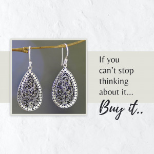 Close-up of ornate silver filigree teardrop earrings with motivational text.