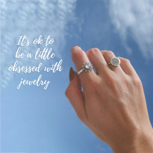 Hand with silver rings against a blue sky background with text overlay.