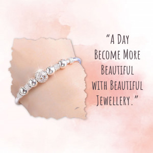 Silver bracelet with charms on a peach background with text 'A Day Become More Beautiful with Beautiful Jewellery'
