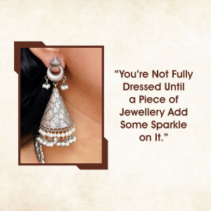 Close-up of silver earrings with a quote about jewelry