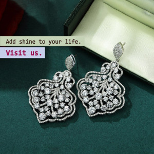 Close-up of ornate diamond earrings on a green velvet background with promotional text.