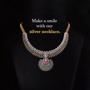 Close-up of a silver necklace with a ruby and diamond pendant against a black background.