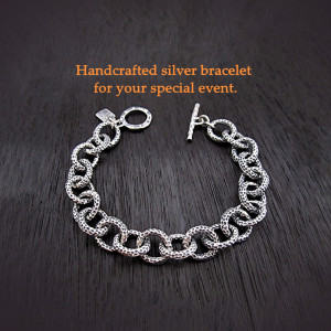 Close-up of a silver link bracelet on a dark wood surface