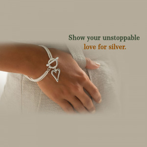 Close-up of a silver bracelet with a heart charm on a woman's wrist