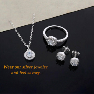 Silver necklace, ring, and earrings set on a black and beige background