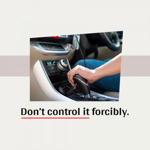 Close-up of a hand shifting gears in a car with a warning message.