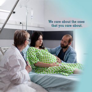 Doctor talking to pregnant woman and her partner in a hospital room.