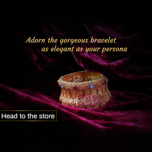 Close-up of a gold bracelet with red and blue gemstones on a dark purple fabric background.