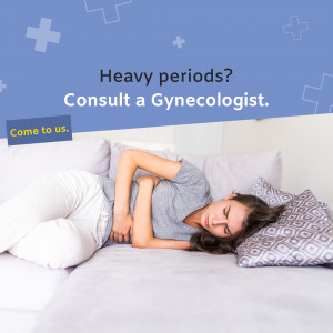 Woman experiencing period pain lying on a couch, promoting gynecologist consultation.