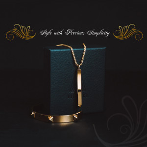 Close-up of a gold necklace and bracelet on a teal box