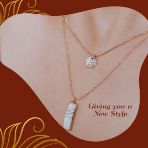 Close-up of a woman wearing two delicate gold necklaces with white marble pendants.