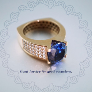 Close-up of a gold ring with a large blue sapphire and diamond accents