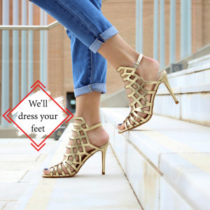 Close-up of a woman wearing stylish gold strappy high heel sandals.