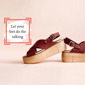 Close-up of stylish red leather platform sandals on a light pink background.