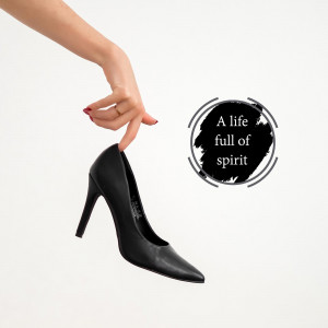 A hand holding a black high heel shoe with a motivational quote.