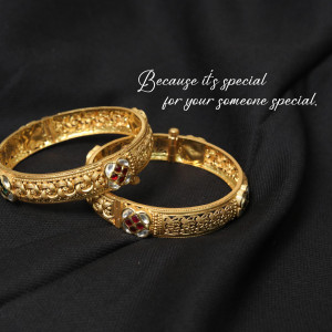 Pair of gold bangles with red ruby stones on a black background