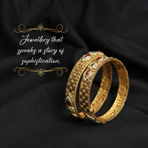 Close-up of two ornate gold bangles with red and white gemstones.