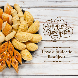 Assortment of Middle Eastern sweets and pastries with a 'Happy New Year' greeting.