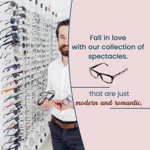 Man holding eyeglasses in front of a display of various spectacles.