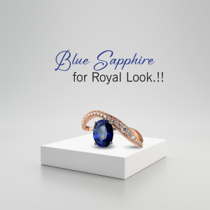 Close-up of a rose gold ring with a large blue sapphire gemstone on a white pedestal.