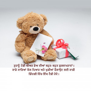 A plush teddy bear sitting with a gift box and a card.