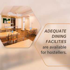 A well-lit dining hall in a hostel with wooden tables and chairs.