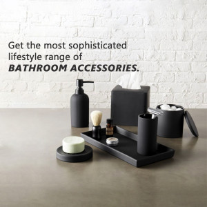 Black bathroom accessories including soap dispenser, toothbrush holder, and tray on a gray surface.