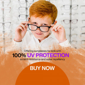 A young boy with red hair trying on black-framed sunglasses, promoting sunglasses for kids with UV protection.