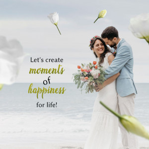 A couple embracing in a field with flowers and a beach in the background.