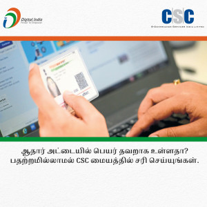 Hands holding a smartphone displaying an Aadhaar card with a laptop in the background.