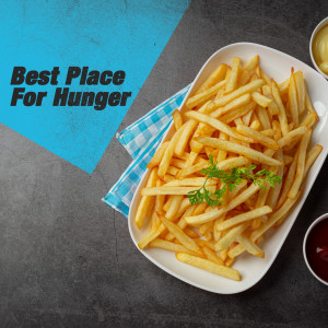 Close-up of a white plate filled with golden, crispy French fries with a small garnish of parsley and a side of ketchup.