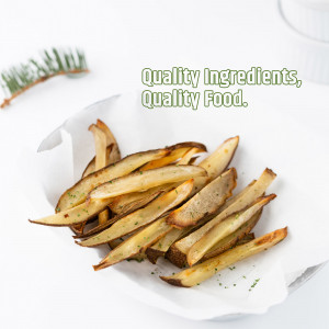 A close-up of a small paper container filled with golden-brown, freshly cut potato fries sprinkled with herbs.