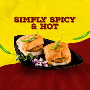 Close-up of two Vada Pavs garnished with green chilies and onions on a black plate.