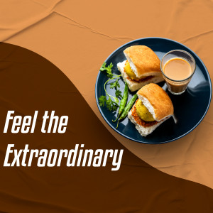 A top-down view of two Vada Pavs on a blue plate with green chilies and a glass of tea.