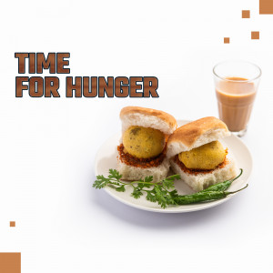 Close-up of Vada Pav with a glass of tea on a white plate.