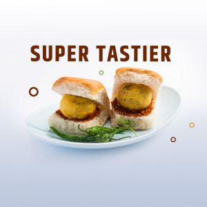 Two Vada Pavs on a plate with green chilies