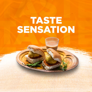 Close-up of two Vada Pavs with a glass of tea on a traditional plate.