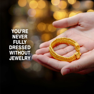 A hand holding a golden bracelet with text 'You're Never Fully Dressed Without Jewelry'