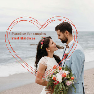 Couple smiling at each other on a beach in the Maldives with a heart outline.